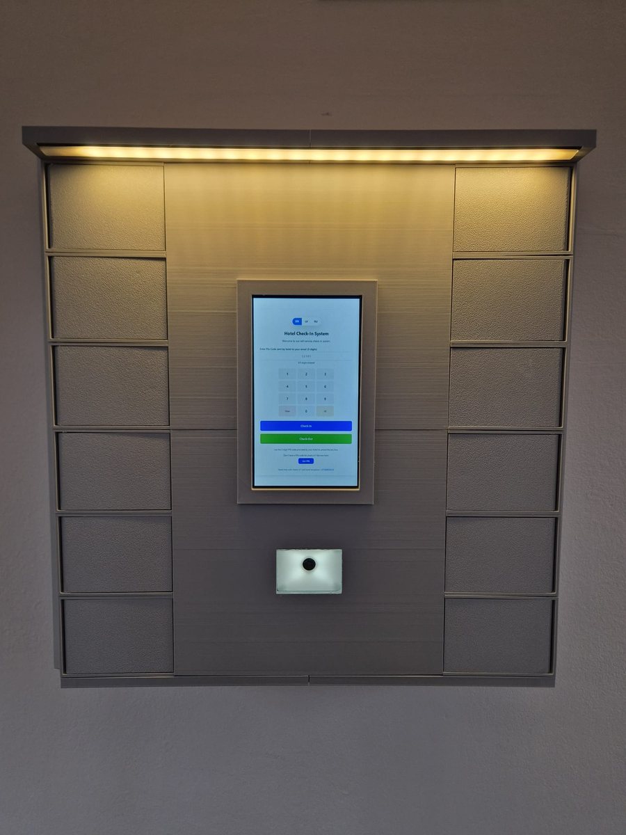AccoBox installed on a hotel wall, with the lit canopy and the PIN check-in screen